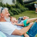 A joyful moment between a grandfather and grandson relaxing outdoors on a sunny day.