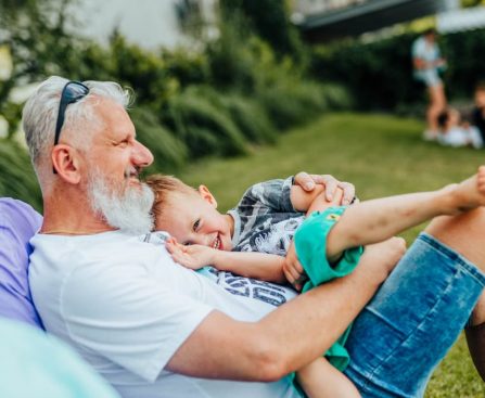 A joyful moment between a grandfather and grandson relaxing outdoors on a sunny day.