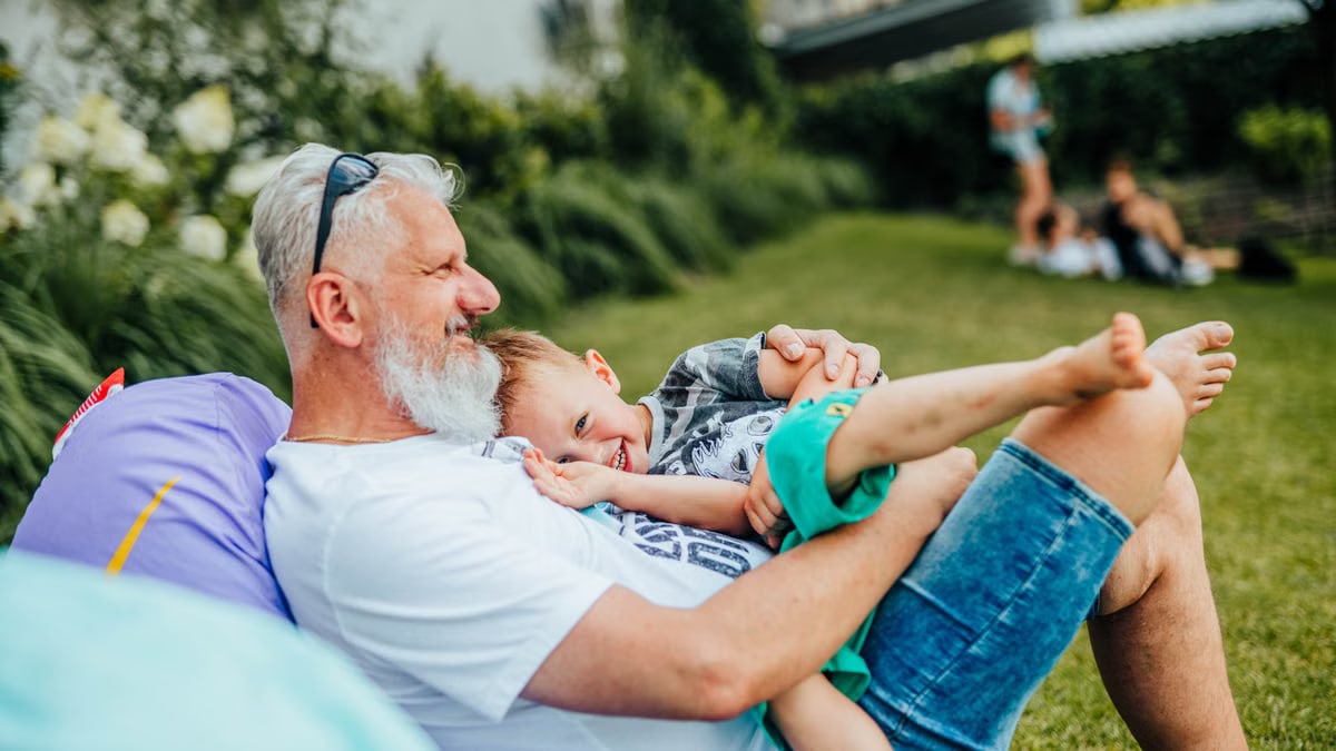 A joyful moment between a grandfather and grandson relaxing outdoors on a sunny day.