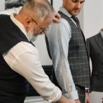 Professional tailor measuring client for a bespoke suit in a modern atelier.