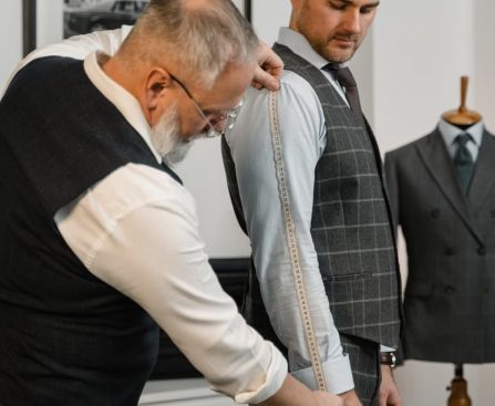 Professional tailor measuring client for a bespoke suit in a modern atelier.